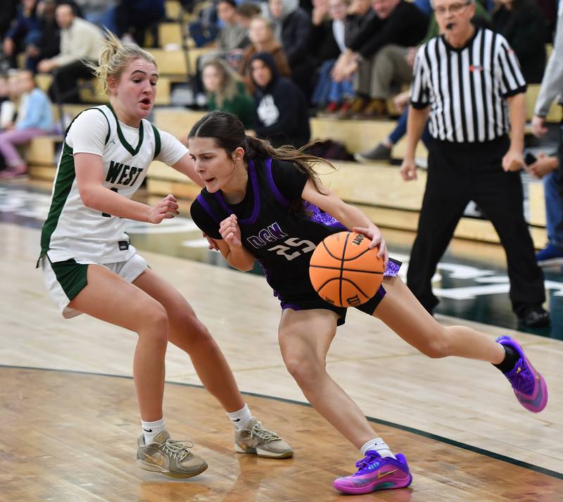 Downers Grove North’s Caitlin Sandridge (25) drives as Glenbard West’s Nina Hendricksen defends during a game on December 4, 2025 at Glenbard West High School in Glen Ellyn.