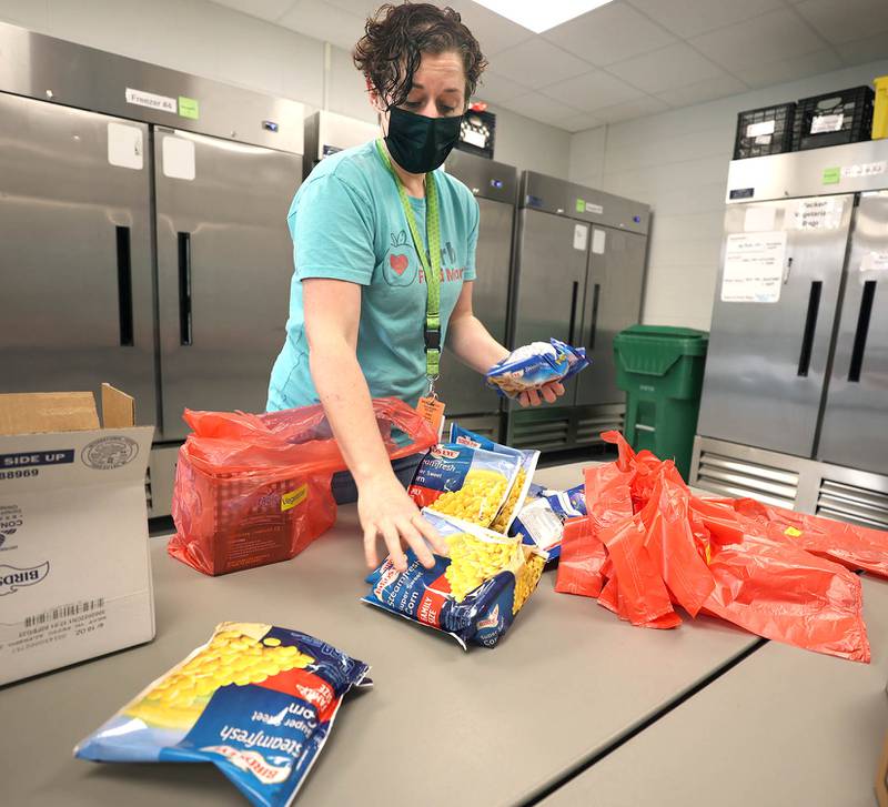 Joey Moore, director of Barb Food Mart, puts frozen corn in the vegetarian bags Thursday, April 7, 2022, at the facility in DeKalb. Barb Food Mart is a food pantry serving those in need that have a student enrolled in the DeKalb School District.