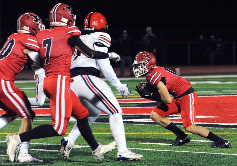 Yorkville defender Tristan Whisenant (12) secures an interception against Bolingbrook on Friday, Sept. 27, 2024, during a varsity game at Yorkville High School.