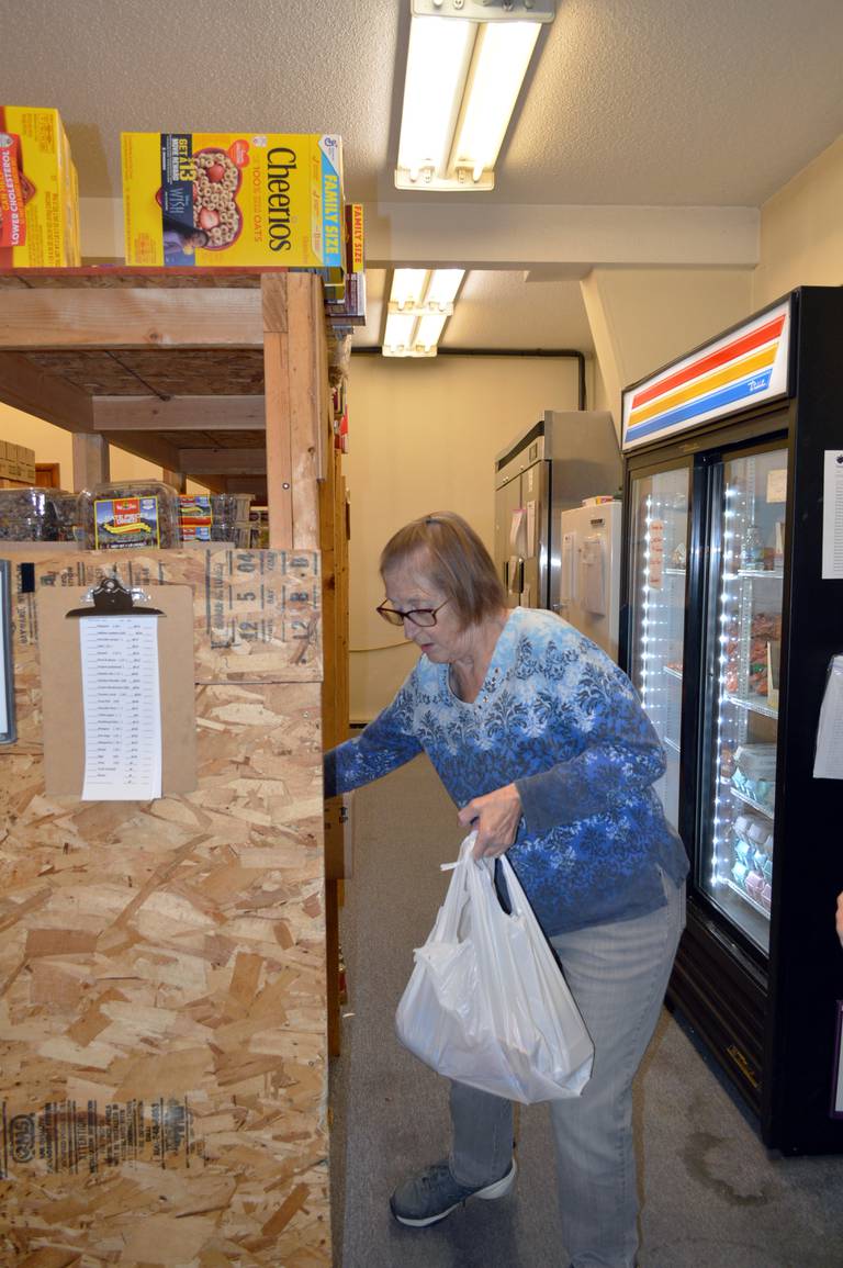 Dixon Community Food Pantry distribution team volunteer Jackey Phillips, of Dixon, grabs food to fill a bag that will go to a family in need on Friday, Nov. 10, 2023.