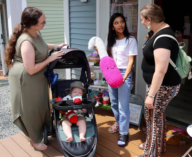 Stephanie from Stitched by Stephanie chats with Jessie and Sebastian Gordon and Sarah Porter during Boo Boo Days shopping in Batavia on Sunday, July 13, 2025.