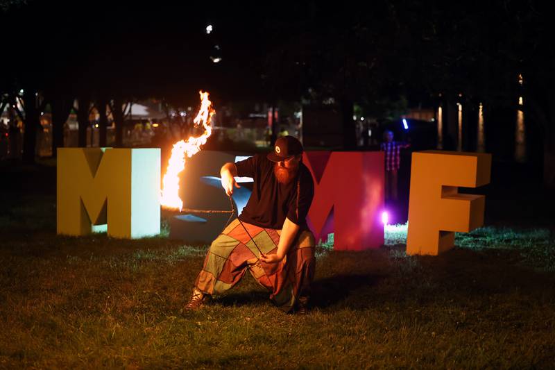 Christopher Becker, with Intrinsic Arts, spins fire poi near the festival's art installation during Merchant Street MusicFest on Friday, July 25, 2025.