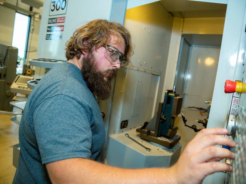 An Illinois Valley Community College student sets up on a horizontal machining center in the CNC lab. Learning to ‘tram’ or square a vise is a skill machinists learn early on, said instructor Scott Fox.