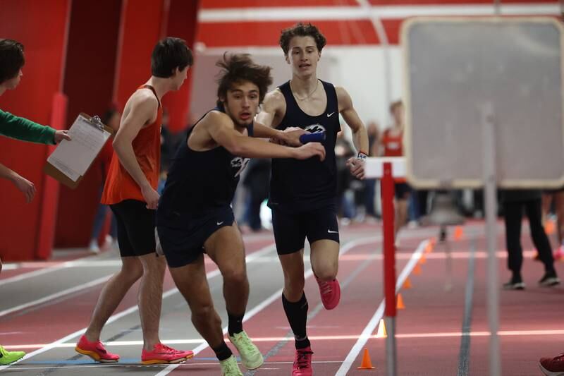 Plainfield South’s Gavin Borger hands the baton off to Ethan Reynoso in the 4x800 meter relay during the Southwest Prairie Conference Indoor Track and Field Meet at Lewis University in Romeoville.