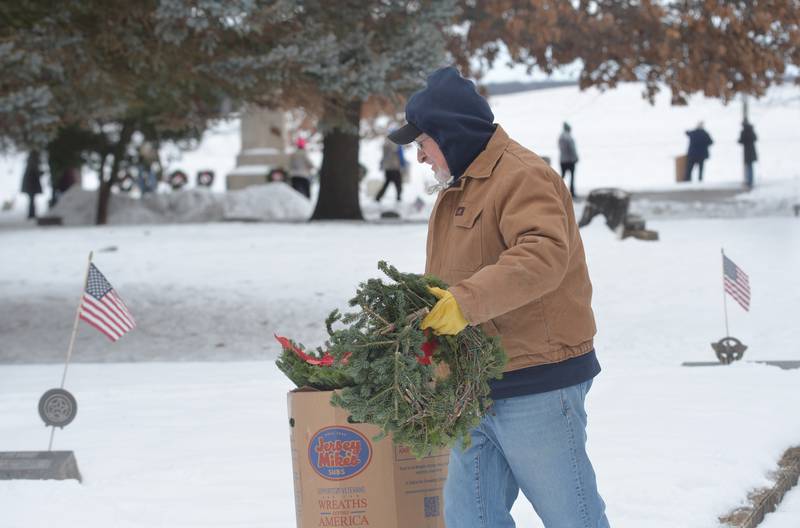 Veteran Don Stevens of Oregon carries a wreath to a veteran's grave at the Daysville Cemetery during the Wreaths Across America program on Saturday, Dec. 13, 2025.
