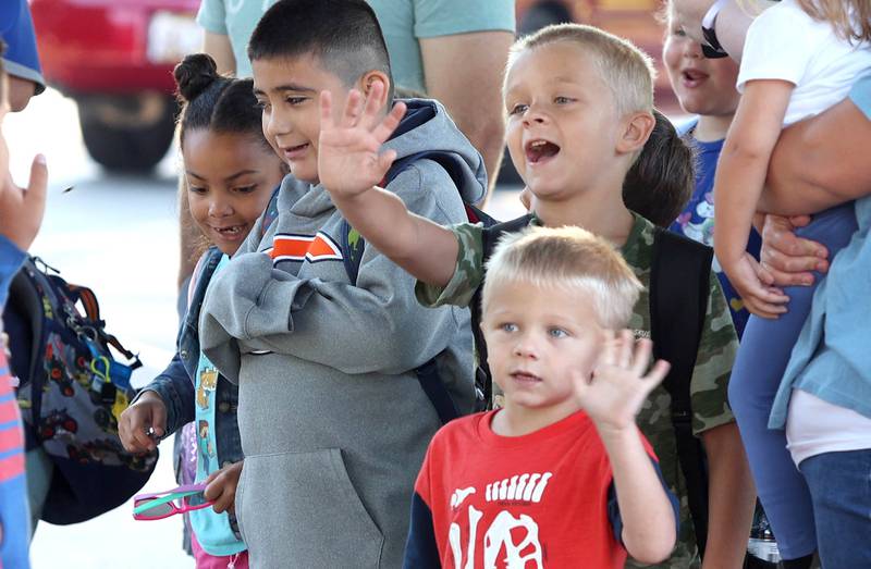 Students wave to their friends on the first day of school Tuesday, Aug. 16, 2022, in front of Genoa Elementary School.