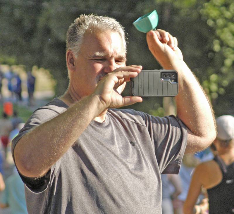 Mike Reed rings a cowbell while taking video of Reagan Run 5K runners Saturday, July 5, 2025, in Dixon.