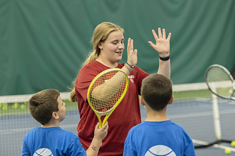 Tennis volunteer Ellie Aitken high-fives her students as they won a round of best backhands Thursday, June 29, 2023 at Westwood.