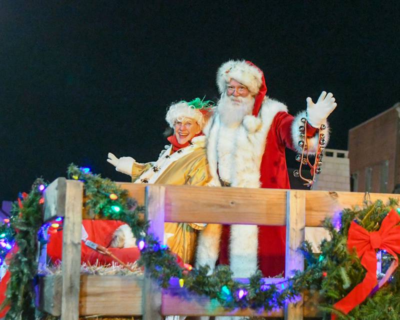 Santa and Mrs. Clause smile for the camera as they travel through downtown Wheaton during the holiday parade on Friday Nov. 24, 2023.