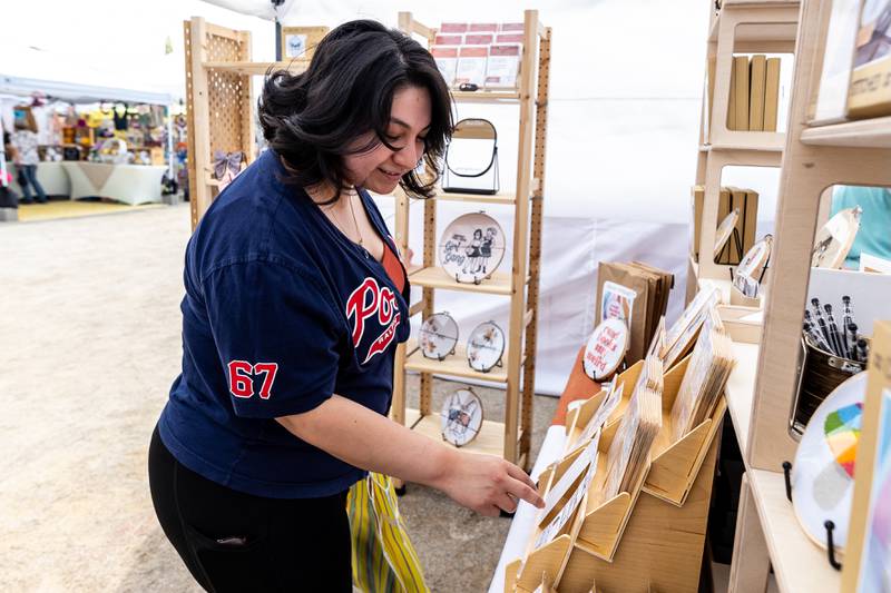 Joliet resident Justina Nava checks out the offerings at the I Got You in Stitches booth at the artisan market during Old Canal Days in Lockport on June, 7, 2025.