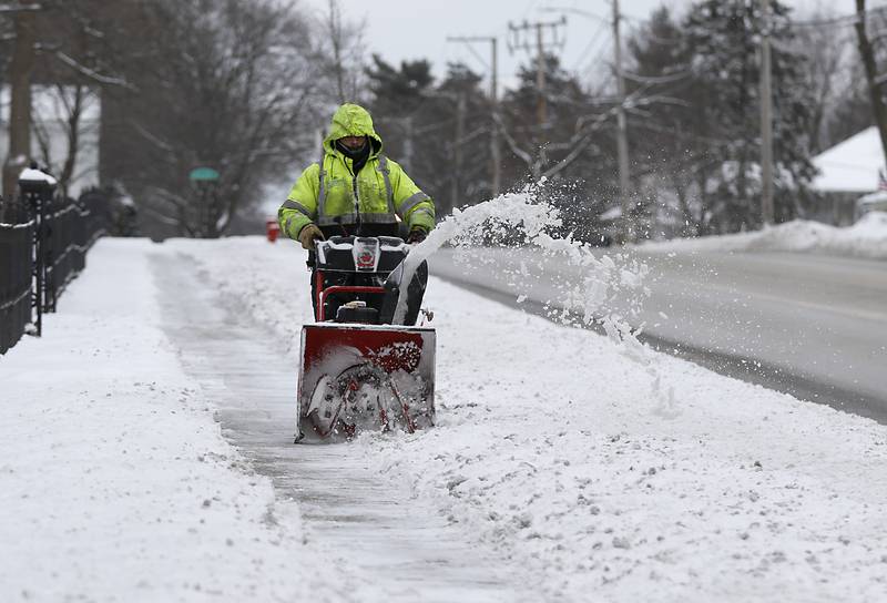 Roberto Rubi clears the sidewalk in front of St. Mary’s Episcopal Church on McHenry Avenue in Crystal Lake on Monday, Jan. 24, 2022, after McHenry County received a fresh snowfall.