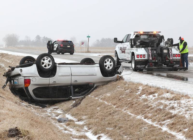 Workers from Tri-State Towing hook up a vehicle that slid off of the roadway and rolled over Thursday, Feb. 16, 2023, as a DeKalb County Sheriff's Deputy closes off Perry Road near Howison Road just south of DeKalb. Winter weather resulted in several crashes in DeKalb County Thursday.