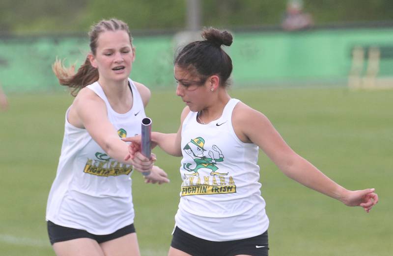 Kankakee McNamara's Izzy Wilkey grabs the baton from teammate Emily Storer in the 4x800 relay during the Class 1A Sectional track meet on Thursday, May 15, 2025 at Seneca High School.