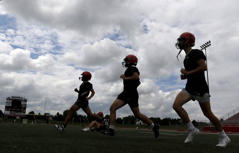 Huntley quarterbacks run during the first day of football practice Monday, August 7, 2023, at the Huntley High School’s Red Raider Stadium.
