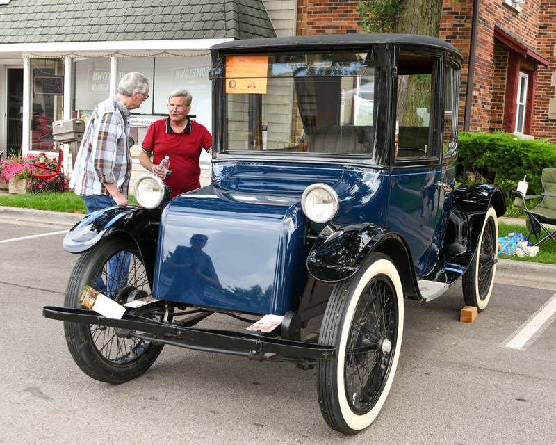 Roger Keys, right, of Geno talks with Frank Giannone of Bloomingdale on Sunday July 27, 2025, of the 1921 Milburn Light Electric car own by the Ellwood house Museum during the Turning back time car show held in downtown Sycamore.
