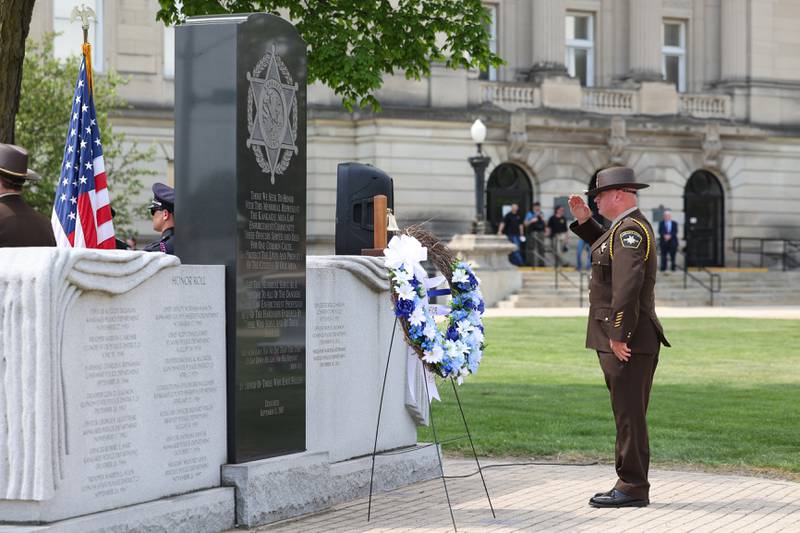 A Kankakee County Sheriff's deputy salutes after placing the wreath near the memorial wall during the annual Law Enforcement Officers Memorial Ceremony honoring Kankakee County officers, held on the lawn of the Kankakee County Courthouse on Thursday, May 15, 2025.