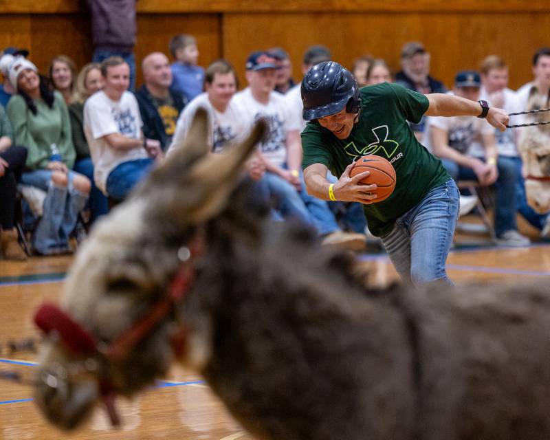 Seneca staff member leads donkey down court whilst holding ball in game of Donkey Basketball on Saturday, Feb. 7, 2026 at Seneca High School West Campus in Seneca.