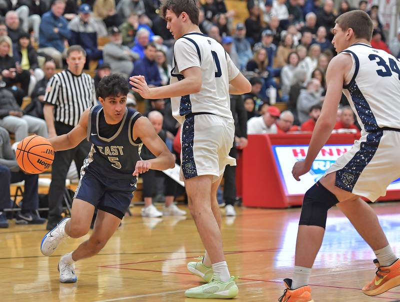 Oswego East’s Ryan Manalodi (5) drives as New Trier’s Owen Foster and Denym Wallace (34) defend during a When Sides Collide Shootout game on January 24, 2026 at Benet Academy in Lisle.