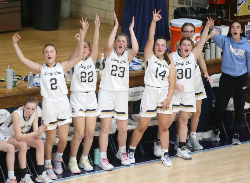 Members of the Marquette girls basketball team cheer on the Lady Crusaders as they play St. Bede on Monday, Nov. 27, 2023 in Bader Gym at Marquette High School.