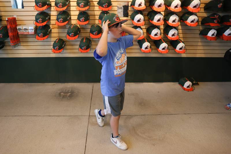 DJ Hesbon, 8, from Plainfield, tries on a hat at the team store before the Joliet Slammers home opener against the Ottawa Titans. Friday, May 13, 2022, in Joliet.
