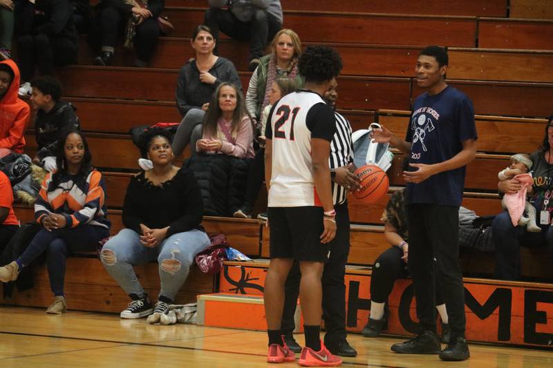 Referee Hakeem Fleming hands the ball to Landen Gladney (right) Dec. 4, 2023 during the annual Guns and Hoses Basketball put on at Huntley Middle School in DeKalb.