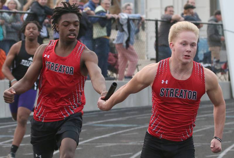 Streator's Collin Jeffries takes the baton from teammate Isiah Brown in the 4x200 meter relay during the Class 2A track sectional meet on Wednesday, May 17, 2023 at Geneseo High School.