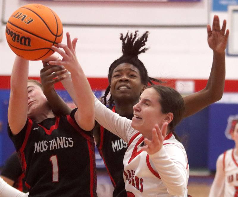 Huntley’s  Alyssa Borzych, right, tussles with Mundelein’s Madelyn Gardner, left, and Grace Dunigan, center, in varsity girls basketball Komaromy Classic tournament  action on Tuesday, Dec. 30, 2025, at Dundee-Crown High School in Carpentersville.