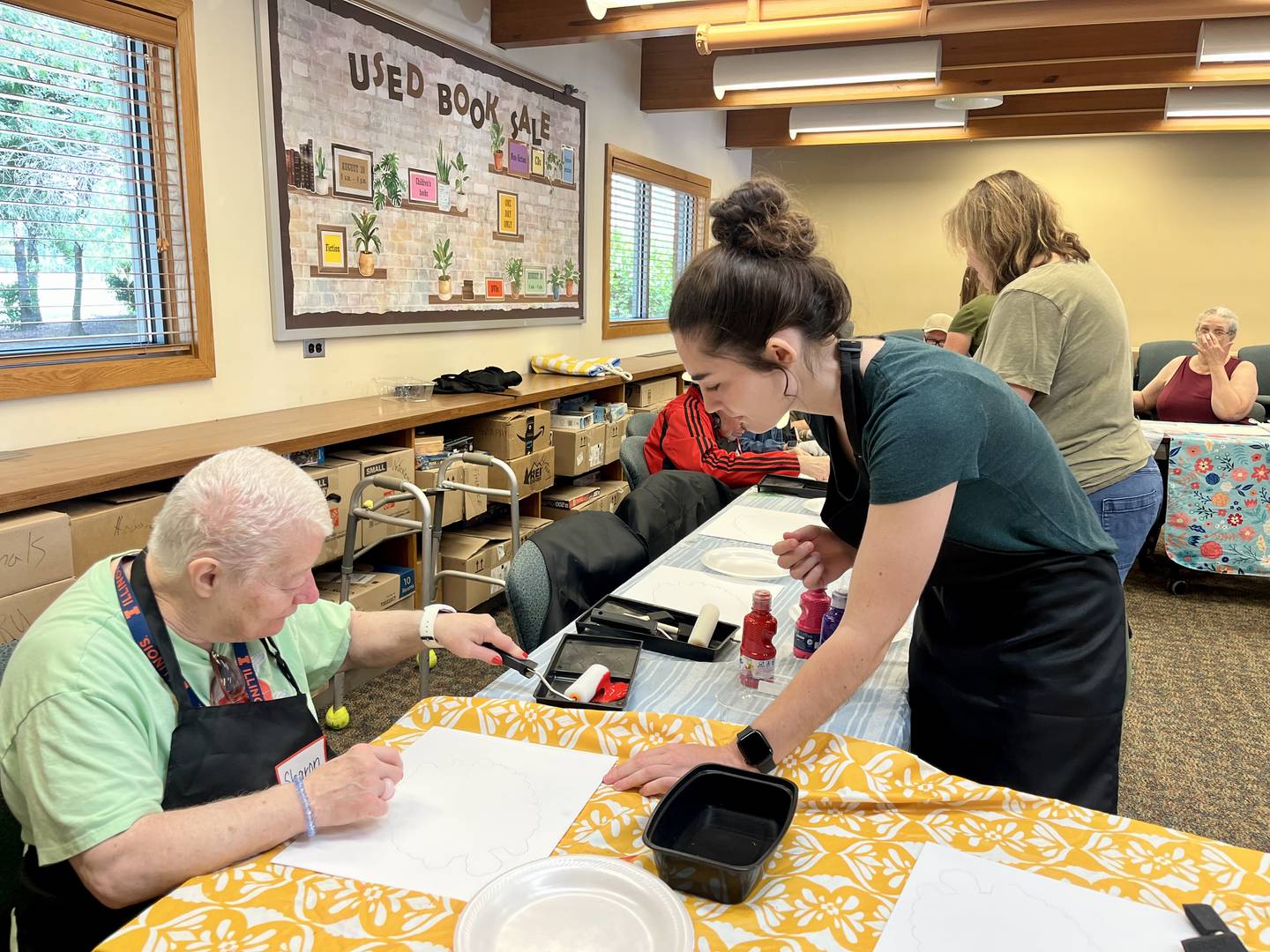 Art instructor volunteer Teresa Murray teaches participants of the "Art for Everyone" tutorial at the Yorkville Public Library how to shape tortoise's onto their canvas backgrounds.