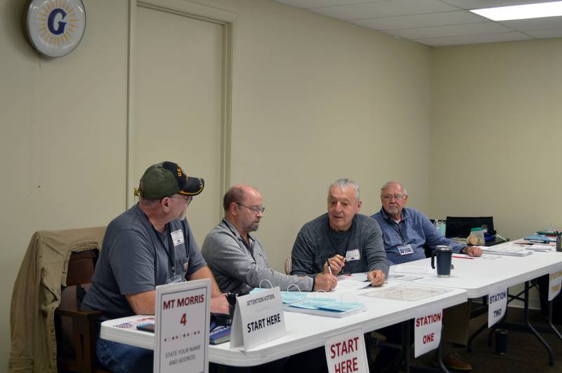 Election judges for Mt. Morris Precinct 4 Richard Weaver (left), Mark Lawler (center left), Harvey Briggs (center right) and John Finfrock examine a list of people who had voted by 11:30 a.m. Tuesday, Nov. 5, 2024.