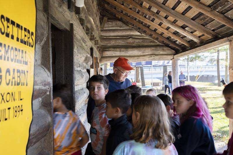 Lee County Historical and Genealogical Society volunteer Gary Michel leads students in the Old Settlers memorial cabin situated at Presidents Park in Dixon. Students also visited the spot where founder John Dixon first set up his homestead, the Dixon Historic Theatre and other buildings in the  downtown.