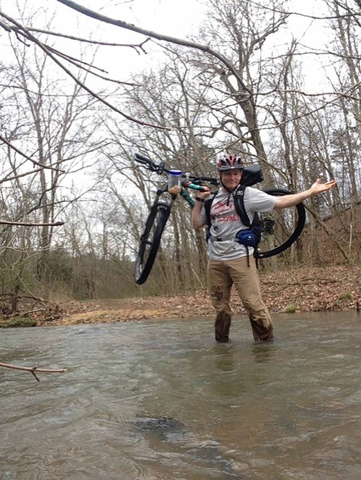 Illinois Valley Community College math professor Wes Black carries his bicycle through a waterway during an adventure race. Beyond his teaching, Black likes to stay active.