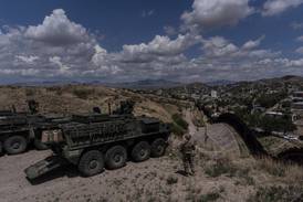 A man is halted climbing the US-Mexico border wall. Under new Trump rules, US troops sound the alarm