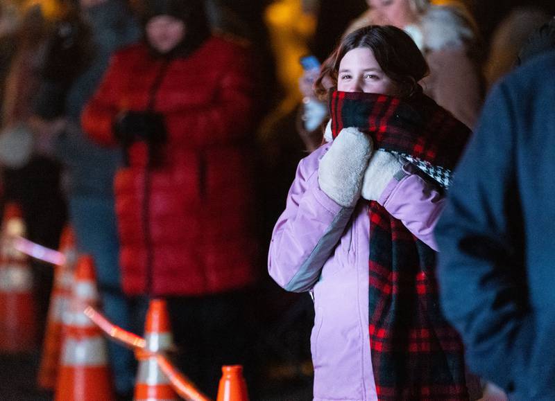 Sophia Malorny, 11, tries to stay warm while watching the Holiday Homecoming Electric Christmas Parade in St. Charles on Saturday, Nov. 30, 2024.