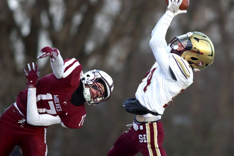 Prairie Ridge’s Logan Harlow, left, watches as St. Ignatius’ Clement Carey hauls in a pass  in Class 6A football playoff semifinal action at Crystal Lake on Saturday.