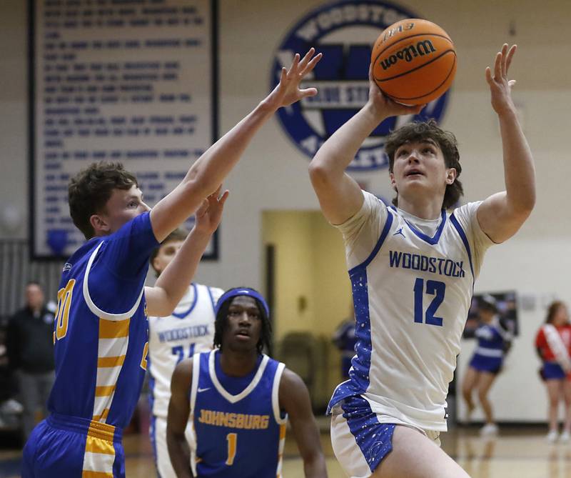 Woodstock's Charlie Walrod shoots the ball as he goes to the basket against Johnsburg's Josh Kaunas (left) during a Kishwaukee River Conference basketball game on Friday,  Feb. 14, 2025, at Woodstock High School.