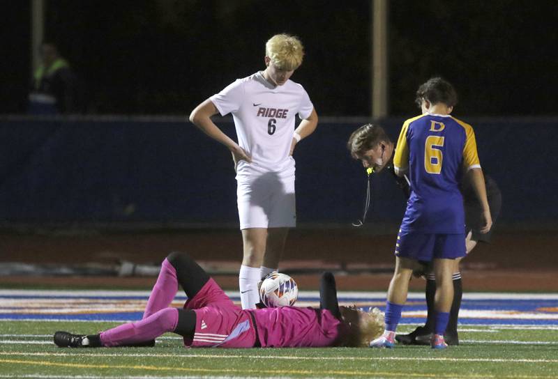 The referee checks on Prairie Ridge's Christopher Zinevich after he was hit by Chicago De La Salle's Alex Panduro during an IHSA Class 2A state semifinal soccer match on Friday, Nov. 8, 2024, at Hoffman Estates High School.