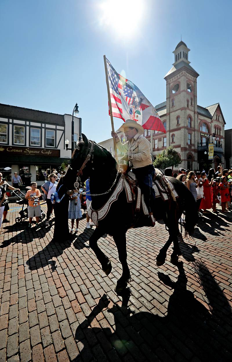 A rider carries a flag around the Historic Woodstock Square during the house parade on Sunday, Sept. 14, 2025,, during the annual Hispanic Connections Mexican Independence Day Celebration.