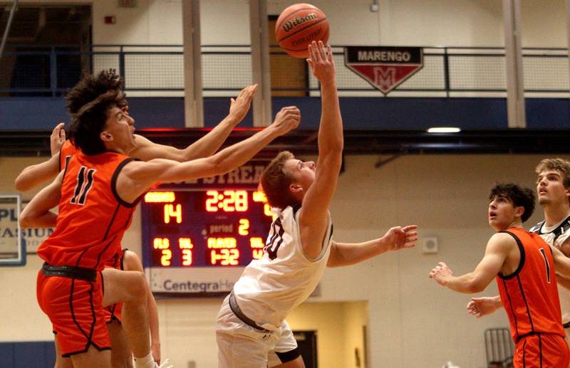 Kaneland’s Troyer Carlson flips the ball to the net as McHenry’s Hayden Stone, left, defends in Hoops for Healing basketball tournament championship game action at Woodstock Wednesday.