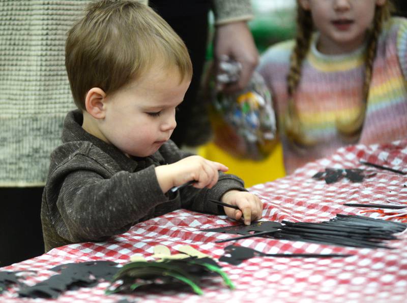 Logan Smith, 2, of Oregon, works on making a Christmas ornament at the Oregon United Methodist Church's Kid's Christmas Carnival during Oregon's Candlelight Walk on Saturday, Nov. 30, 2024.