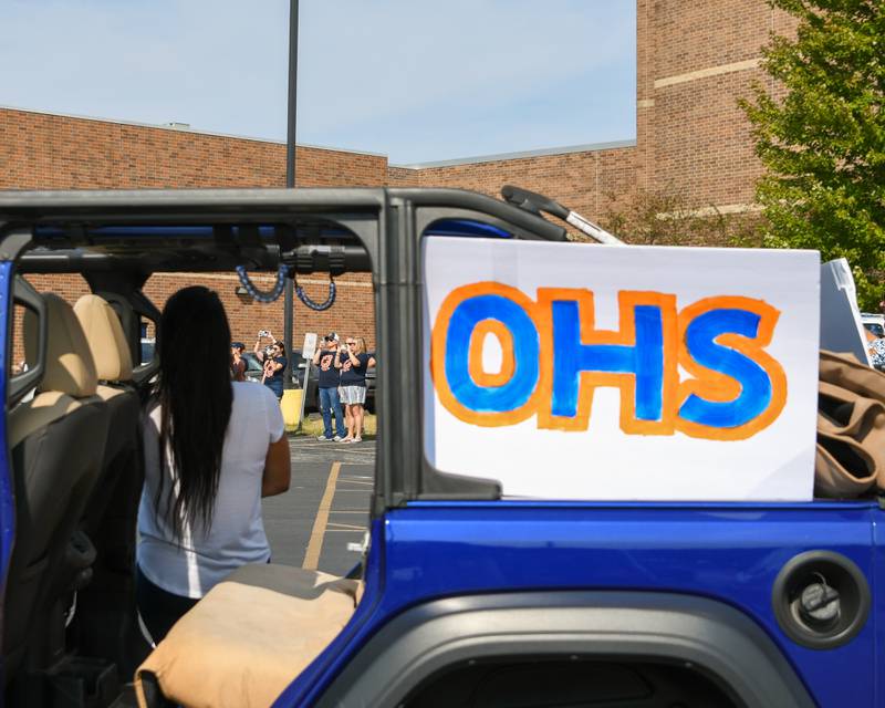 Community members record Oswego High School marching band as they play Amazing Grace on Sunday Sept. 24, 2024, before the start of the homecoming parade to honor an Oswego High School classmate who passed away in a car crash.