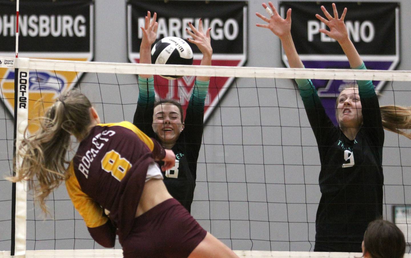 Woodstock North’s Jayden Johnson, center, and Clara Klasek, right, block as Richmond Burton’s Dani Hopp, left, hammers the ball over the net in varsity volleyball action at Woodstock North High School in Woodstock on Wednesday, Oct. 16, 2024.