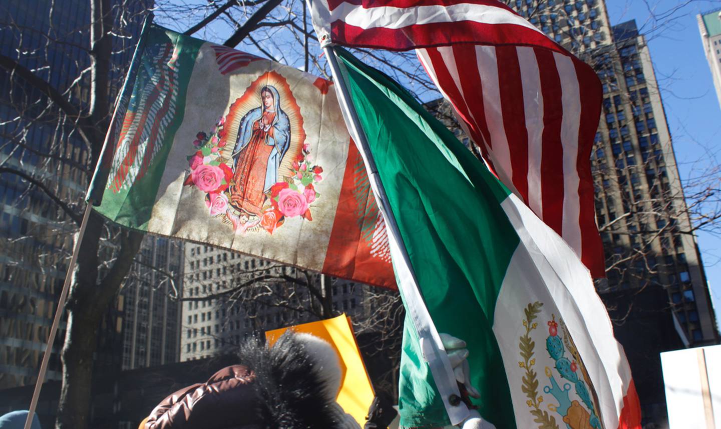 Inauguration Day protesters march in downtown Chicago on Monday, Jan. 20, 2025, with different flags, including the U.S., Mexican and Virgin of Guadalupe flags. They chanted “No hate, no fear” as they moved toward Trump Tower. (Photo by Ashley N. Soriano for Medill Illinois News Bureau)