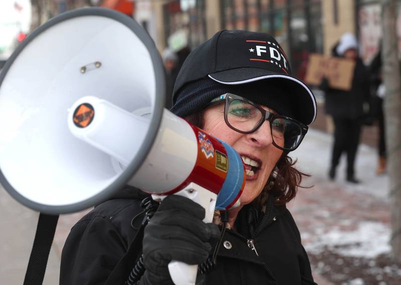 Anna Wilhelmi, head of the DeKalb County Democratic Party, leads the chants as protesters march west down the sidewalk on Lincoln Highway in DeKalb Tuesday, Jan. 20, 2026, as part of a larger national Free America Walkout. The group is protesting what they perceive as an escalating fascist threat under President Donald Trump and his administration.