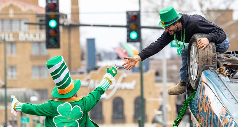 Andrew Lindemann of Chad’s Towing high fives stilt walker Jason Kollum during the St. Charles St. Patrick’s Parade on Main Street in St. Charles on Saturday, March 15, 2025.