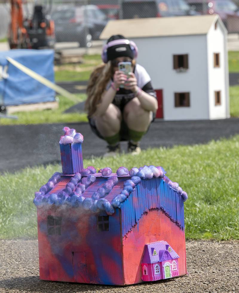 Adalyn Hitt, a junior at Dixon High School, records her burning house model Tuesday, April 22, 2025, outside of Dixon High School. The forensics class at DHS built houses then set them ablaze to study burn patterns as an arson investigation.