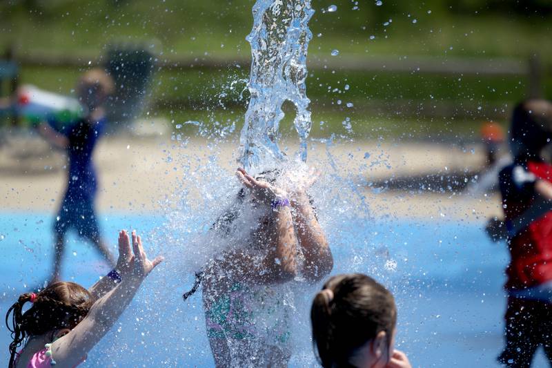 Mia Prendergast, 7, gets hit with a bucket of water at the Westmont Park District’s Ty Warner Park splash pad on Tuesday, June 21, 2022. Temperatures were expected to reach the upper 90s.