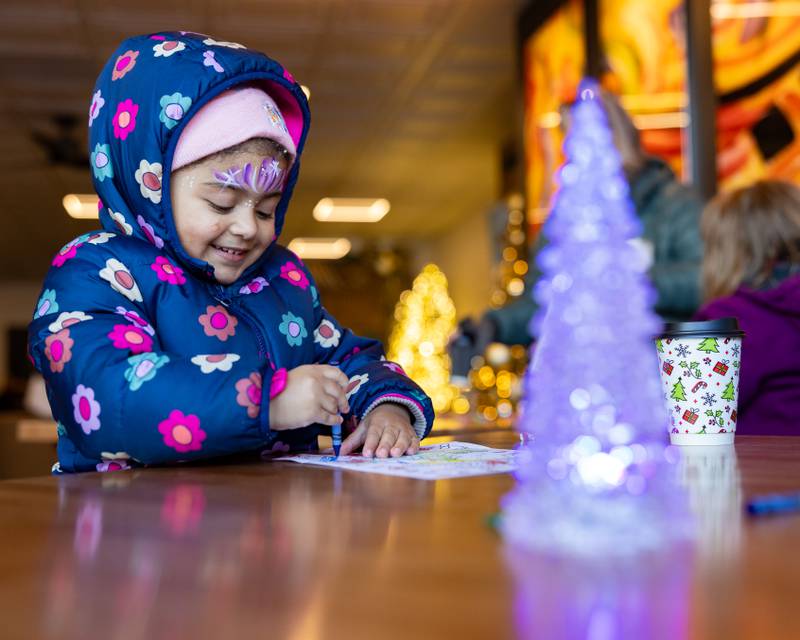 Alayna Cheers, 3, colors a picture prior to the start of the Christmas Parade at the Community Center on December 7, 2025 in Spring Valley.