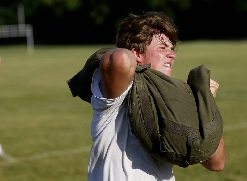 Cary-Grove’s Colin Desmet runs with a weighted bag while doing conditioning drills during summer football practice Thursday, June 30, 2022, at Cary-Grove High School in Cary.