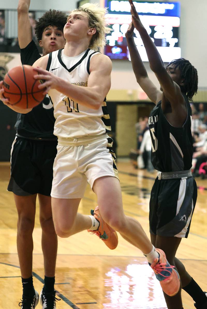 Sycamore's Burke Gautcher gets between Kaneland's Evan Frieders (left) and Kaneland's Freddy Hassan on his way to the basket during their game Friday, Feb. 10, 2023, at Sycamore High School.