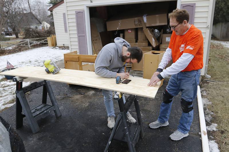 Tanner Ilkow (left) and Jerry Webb, from Home Depot, mark out the cuts they need to make on a sheet of plywood as they instal a new kitchen in veteran Craig Taylor's home on Thursday Jan. 16, 2025. The kitchen remodel for Taylor is part of the 30 Days for 30 Vets program.